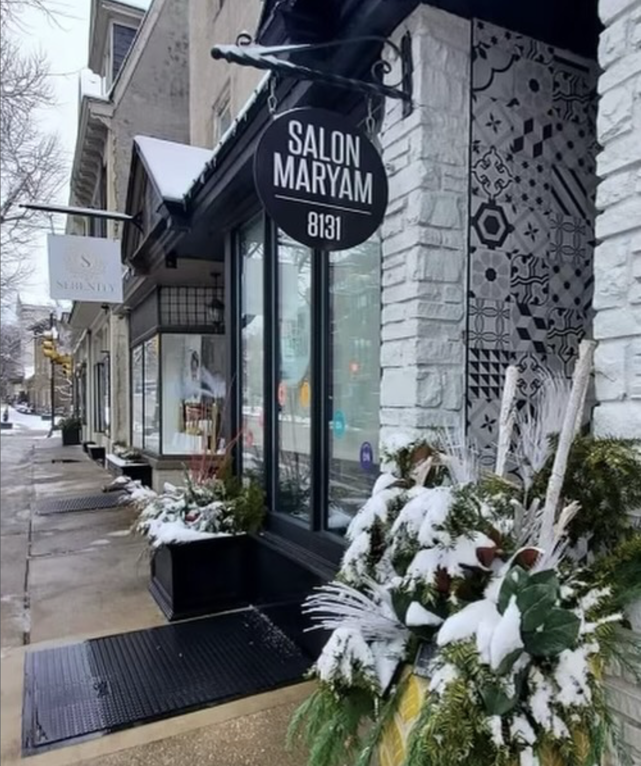 The Salon Maryam storefront on Germantown Avenue with the round sign and winter greenery